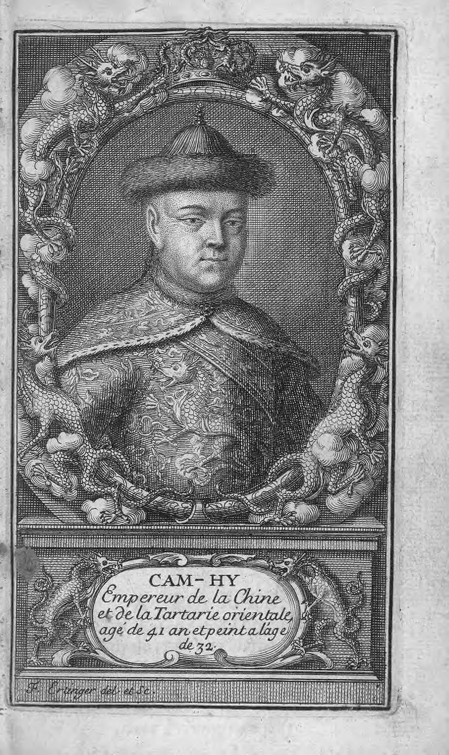 A black-and-white engraved portrait of the Kangxi Emperor in a dragon robe, enclosed by an ornate oval frame of dragons and clouds with a French caption below.